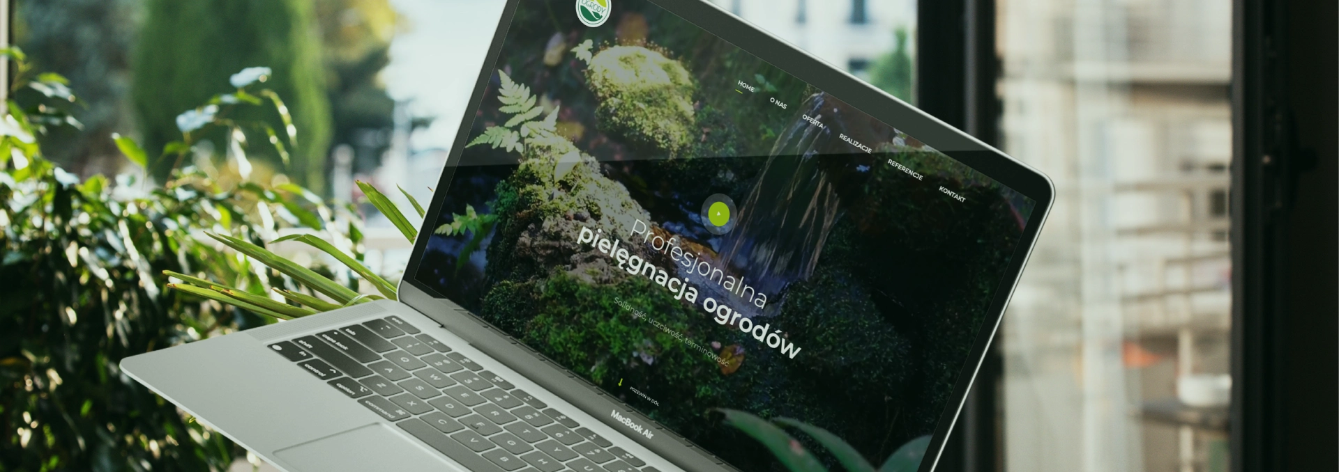 Na zdjęciu widoczna jest strona internetowa firmy zajmującej się profesjonalną pielęgnacją ogrodów. Główna grafika przedstawia wodospad na tle zielonej roślinności, co symbolizuje dbałość o naturę i zieleń.